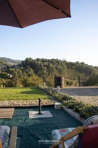 a patio with chairs and an umbrella next to a field at Quinta Dos Sonhos in Vale de Cambra +17 photos