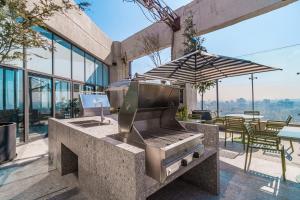 an outdoor kitchen with a grill and an umbrella at Stylish Studio w Gym & Pool Access VIATO HOMES in Mexico City