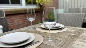 a wooden table with two wine glasses and plates on it at Beachhouse Schwedeneck in Surendorf