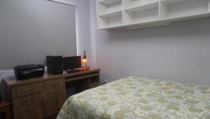 a bedroom with a bed and a desk with a television at Apartamento central próximo ao Shopping Palladium com garagem coberta in Ponta Grossa