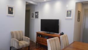 a living room with a television and two chairs at Apartamento central próximo ao Shopping Palladium com garagem coberta in Ponta Grossa