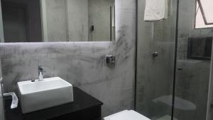 a bathroom with a sink and a glass shower at Apartamento central próximo ao Shopping Palladium com garagem coberta in Ponta Grossa