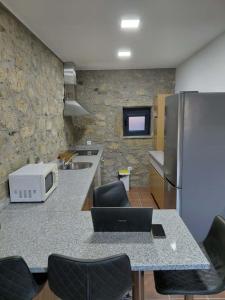 a kitchen with a counter with chairs and a refrigerator at Quinta Dos Sonhos in Vale de Cambra