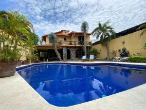 a swimming pool in front of a house with palm trees at nice vacation home in Zihuatanejo