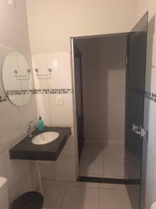 ein Badezimmer mit Waschbecken und Dusche mit Spiegel in der Unterkunft Suítes Recanto das Flores 4 in Pirenópolis
