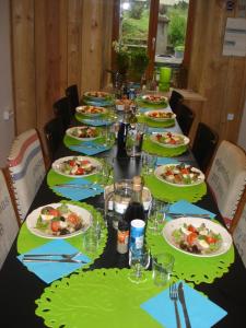 une longue table avec des assiettes de nourriture dans l'établissement Les Deux Vélos Chambres d'Hotes-Table d'Hotes, à Biert