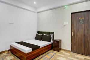 a bedroom with a bed and a wooden door at HOTEL O GOLDEN MAJESTIC in Prayagraj