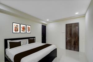 a bedroom with a large bed and a wooden door at SPOT ON Sriman Stay Inn in Hakīmpet +21 photos