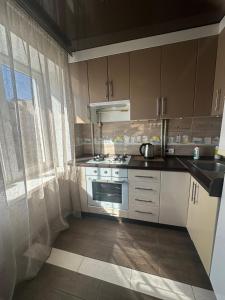 a kitchen with white cabinets and a stove and a window at Коротченко 31 in Golta +12 photos