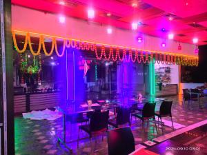 a dining room with purple lights and tables and chairs at Shree Siddhi Vinayak Hotel & Restaurant in Bargi