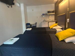 two beds in a small room with a kitchen at Vagabundo Expo Guadalajara in Guadalajara