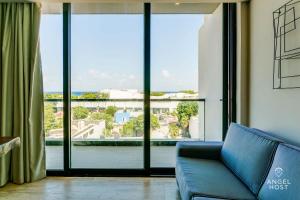 プラヤ・デル・カルメンにあるNEW Downtown Stay with Oceanview Roof Pool and Gym plus Cafeのソファと大きな窓のあるリビングルーム