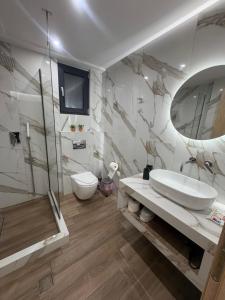 a bathroom with a sink and a toilet and a mirror at Project Georgiadi #1 - Modern Apartment in peaceful neighborhood - 15 mins from Loutra Pozar in Aridaia +16 photos