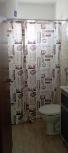 a bathroom with a shower curtain with a toilet at Casas El Timón B in Chuí +5 photos