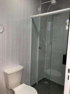 a bathroom with a toilet and a glass shower at Kitnet Nova e Aconchegante in Cachoeira do Sul