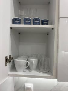 a cupboard with cups and other items in it at Project Georgiadi #2 - Modern Apartment in peaceful neighborhood - 15 mins from Loutra Pozar in Aridaia +20 photos