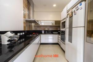 a kitchen with white appliances and a white refrigerator at Casa em Maresias com Churrasqueira e area de lazer in Maresias