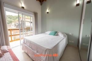 a bedroom with a bed and a large window at Casa em Maresias com Churrasqueira e area de lazer in Maresias