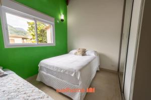 a green room with two beds and a window at Casa em Maresias com Churrasqueira e area de lazer in Maresias