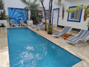 Una piscina con tumbonas frente a un edificio. en Brisa de Alma Guesthouse, en Bayahibe
