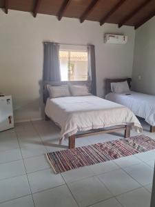 ein Schlafzimmer mit zwei Betten und einem Fenster in der Unterkunft Suítes Recanto das Flores 3 in Pirenópolis