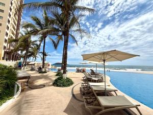 a pool with chairs and umbrellas next to the ocean at Park Royal 809 Vista al Mar in Mazatlán