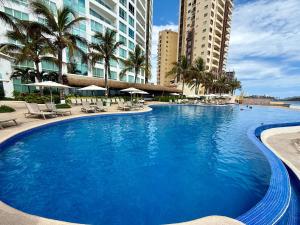 a large swimming pool with palm trees and buildings at Park Royal 809 Vista al Mar in Mazatlán