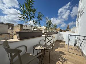 a balcony with chairs and tables on a roof at Bentley Floriana Suites in Il-Furjana