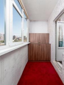 a room with a red carpet and two windows at Апартамент с восхитительным видом на горы и огни города in Almaty
