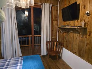 una camera con letto, TV e sedia di Pousada Lua Cheia Caraíva a Caraíva