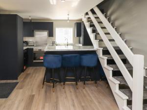 a kitchen with blue bar stools and a kitchen with a staircase at Seaspray in Beadnell
