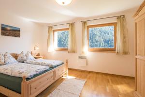 ein Schlafzimmer mit einem Bett und zwei Fenstern in der Unterkunft Chalet Leitn-Anger in St. Leonhard in Passeier