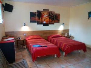 two beds in a room with red sheets at Les Balisiers a 450m de la plage in Deshaies