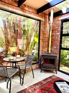 Un patio con mesa y sillas y una chimenea. en The Secret Garden Hideaway, en Mossel Bay