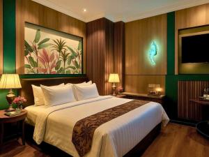 a bedroom with a large bed and a painting on the wall at Bona Ventura Hotel & Skybar in Tanjung Pinang
