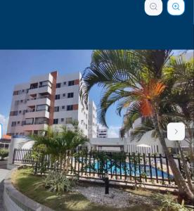 ein Gebäude mit einer Palme vor einem Zaun in der Unterkunft Apto 2 suítes em Aracajú a 300 metros da Orla in Aracaju