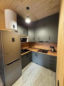 La cuisine est équipée de placards gris et d'un réfrigérateur en acier inoxydable. dans l'établissement Good Home in Dendropark, à Stepanavan