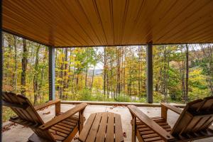 two chairs and a table on a porch with trees at Spacious 6 Bedroom Chalet Near Holiday Valley in Ellicottville