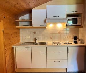 a kitchen with white cabinets and a sink at Haus Kanisfluh in Au im Bregenzerwald