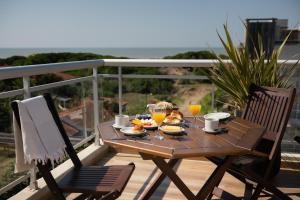 a wooden table with food and drinks on a balcony at Terrazas Ostende - Apart Hotel in Ostende