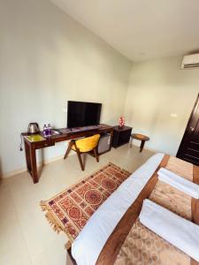 a living room with a bed and a television at Beachwaves cottages by Tvessa in Morjim