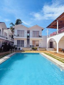 a swimming pool in front of a house at Beachwaves cottages by Tvessa in Morjim