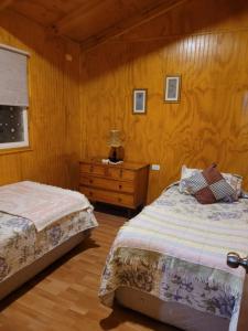 a bedroom with two beds and a table with a lamp at CABAÑAS RINCON SOLEADO, Chile Chico in Chile Chico