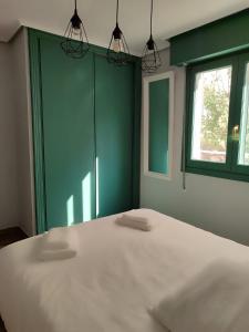 a bedroom with a large white bed with a green wall at El Soto in Villarcayo