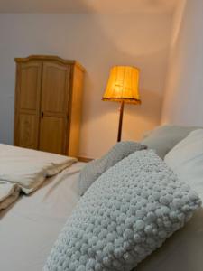 a white blanket laying on a bed with a lamp at Gemütliches Buchen Zimmer mit Gemeinschaftsbad in Karlsruhe