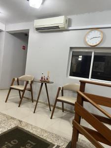 a room with two chairs and a table and a clock at Rosário Park Hotel in Rosário do Sul
