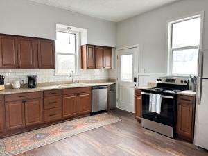 a kitchen with wooden cabinets and a stove top oven at Modern 4 BDRM Renovated Spacious near U of E and Downtown in Evansville +20 photos