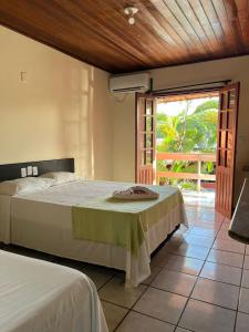 a bedroom with a large bed and a balcony at Hotel Recanto Do Sol in Porto Seguro