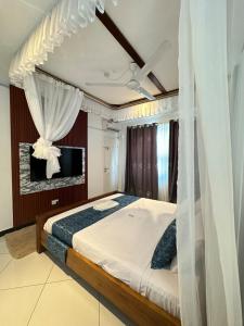 een slaapkamer met een bed met gordijnen en een televisie bij Nyumba Alfajiry in Malindi