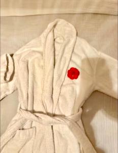 a white robe with a red button on a bed at Grande maison romantique avec jacuzzi intérieur & parking, à 1h30 de Paris in Montbouy